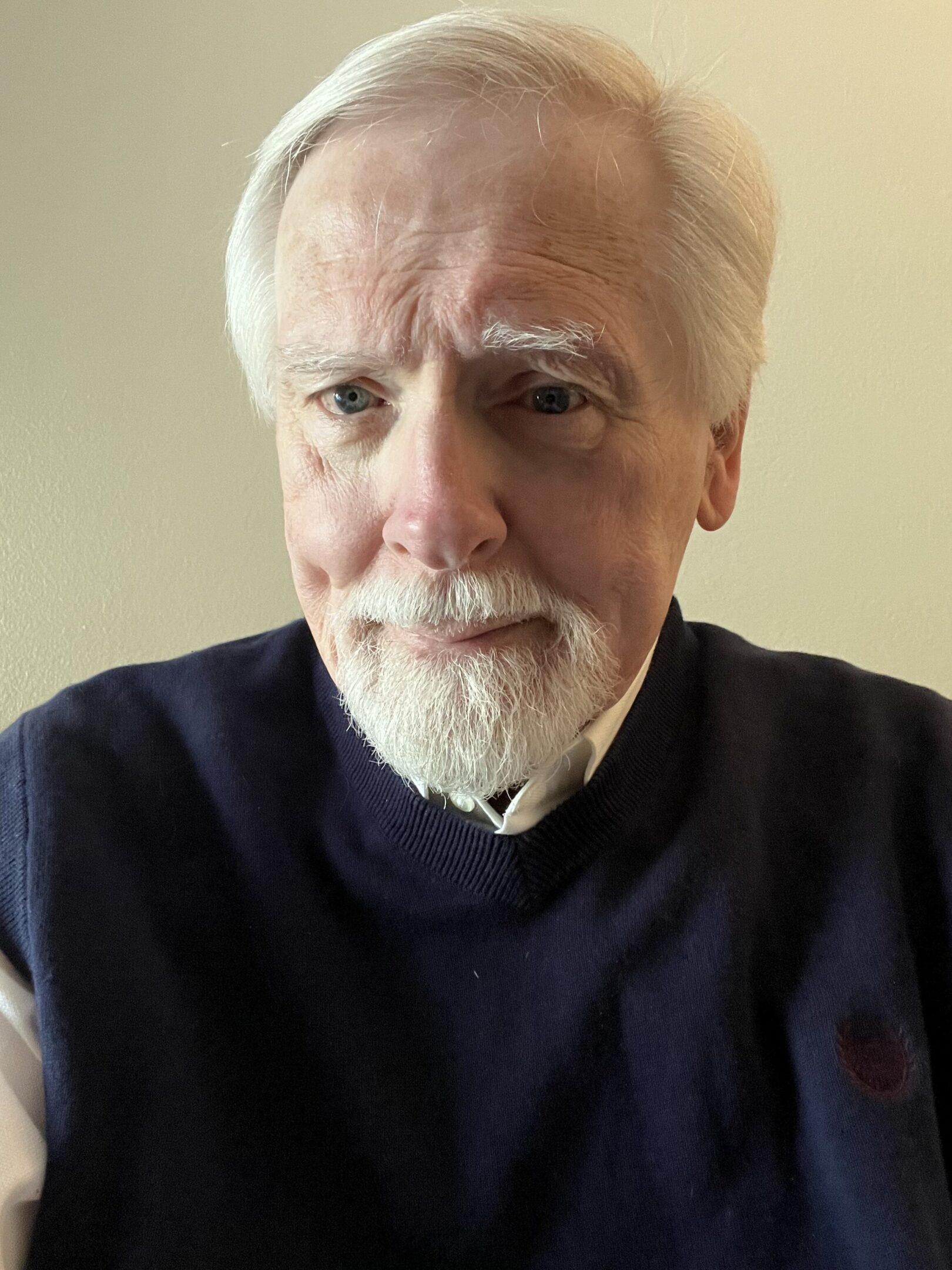 Portrait of an elderly man with white hair and beard wearing a dark sweater.